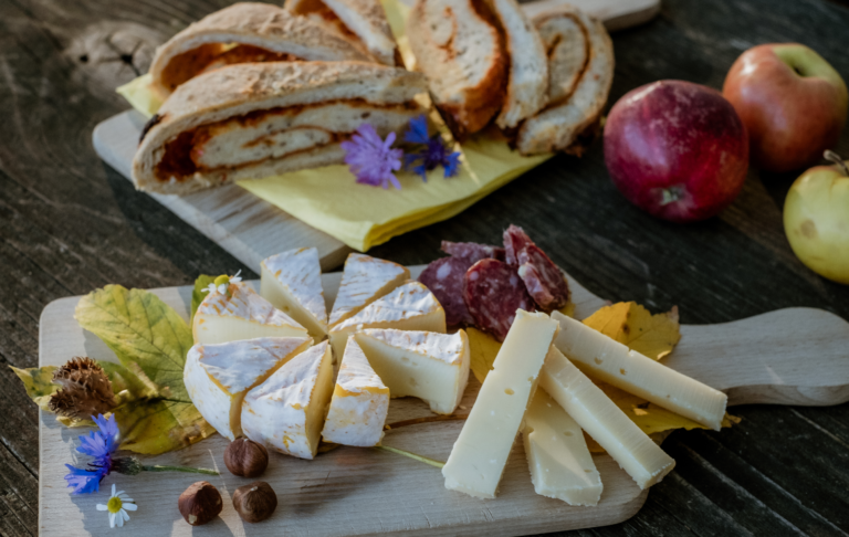 Käse, Bro, Nüsse und Früchte auf einem Holzbrett angerichtet.