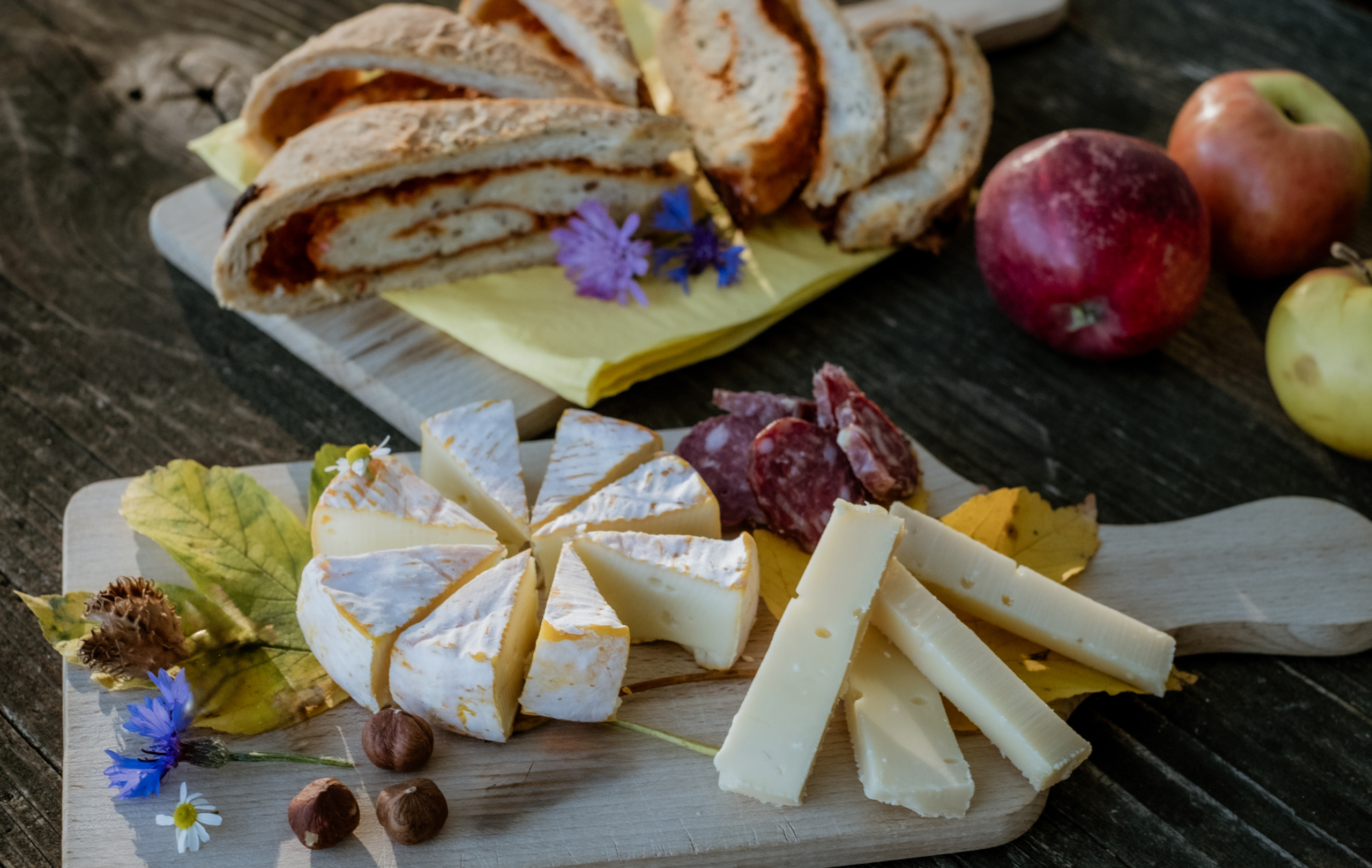 Käse, Bro, Nüsse und Früchte auf einem Holzbrett angerichtet.
